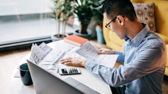 Man using smart phone and laptop for managing finances