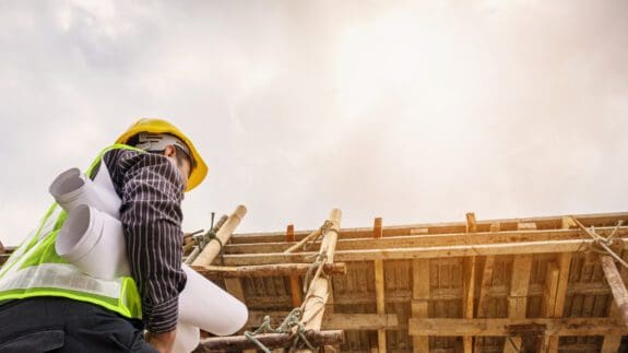 builder on construction site with blueprints