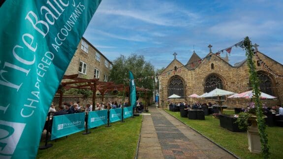 Price Bailey outdoor event with banners, attendees, and historic stone building backdrop