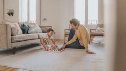 A man and a young child sitting on the floor playing